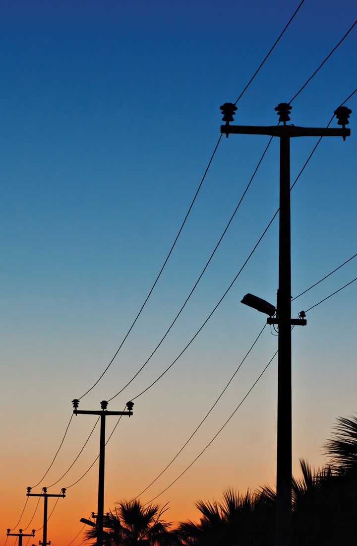 View of the shadow of a row of transmission towers against a sunset 