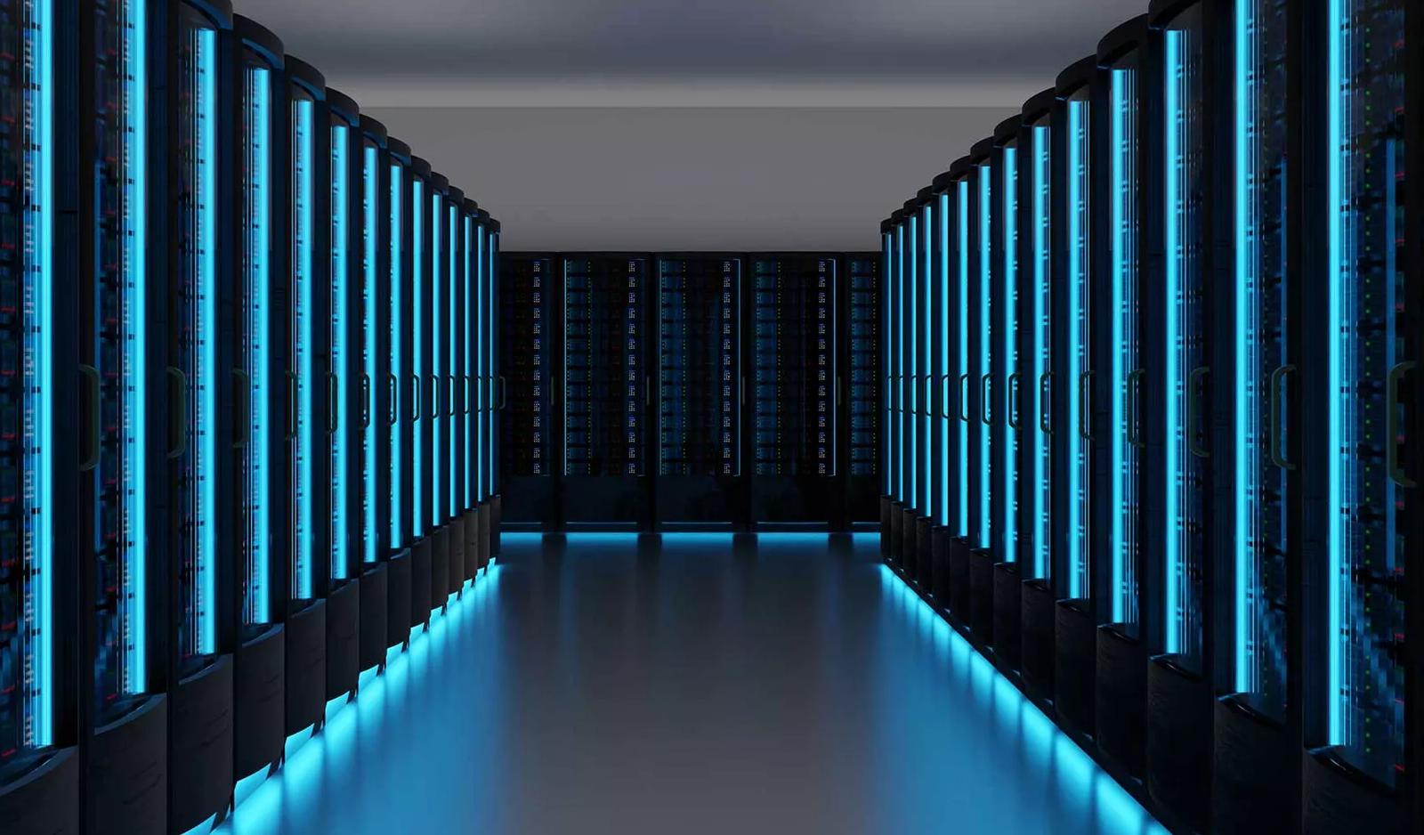 A perspective shot down a long aisle between two rows of dark server racks. The racks are illuminated by vertical strips of intense blue LED light.