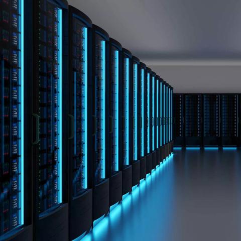 A perspective shot down a long aisle between two rows of dark server racks. The racks are illuminated by vertical strips of intense blue LED light.