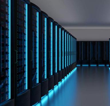 A perspective shot down a long aisle between two rows of dark server racks. The racks are illuminated by vertical strips of intense blue LED light.