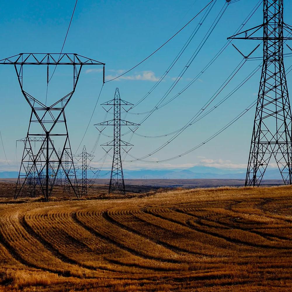Aerial view of multiple transmission towers in a grassy field, under a blue sky.