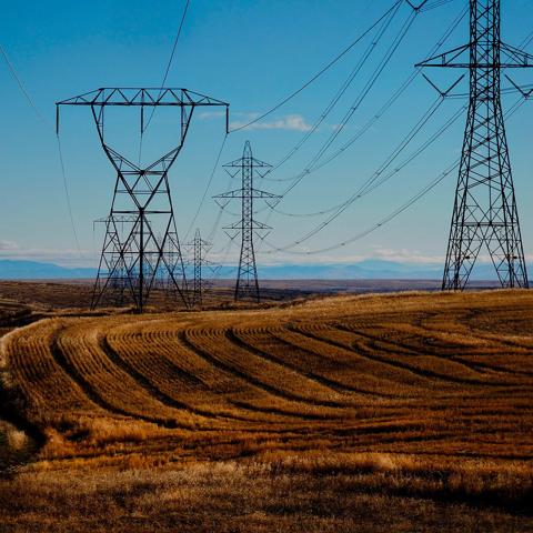 Aerial view of multiple transmission towers in a grassy field, under a blue sky.