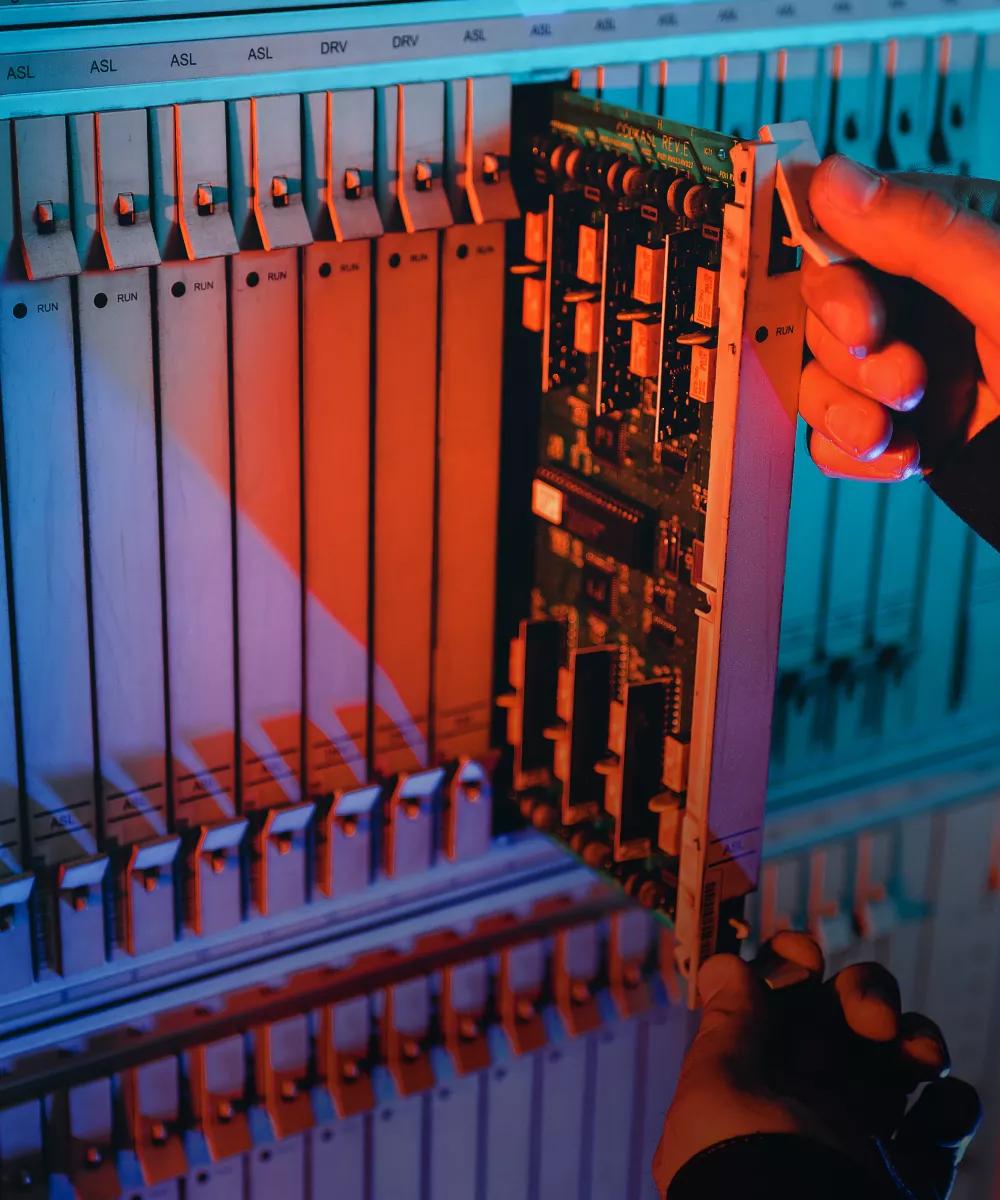 A hand pulling a switch in a row of switches with red lighting from a data center