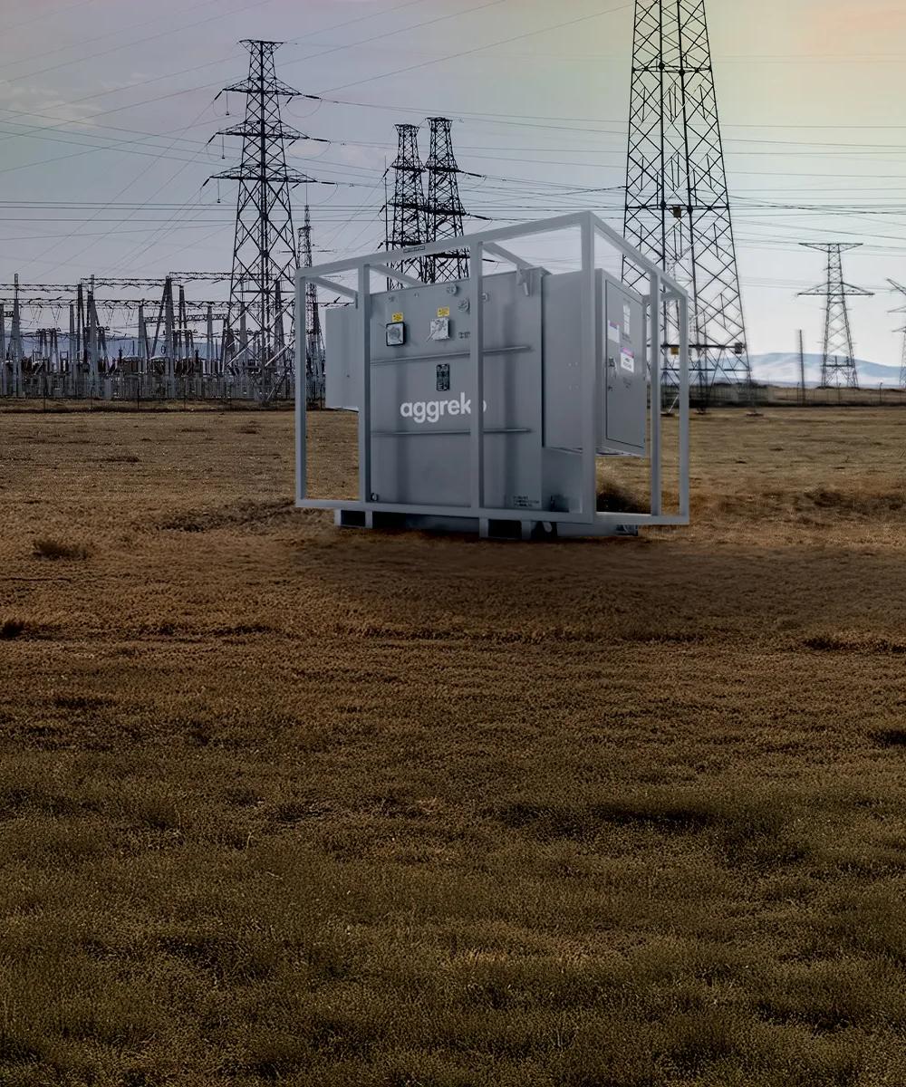 Transformer in a field with a power plant in the background