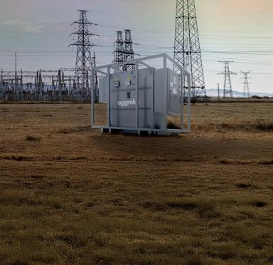 Transformer in a field with a power plant in the background