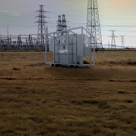 Transformer in a field with a power plant in the background