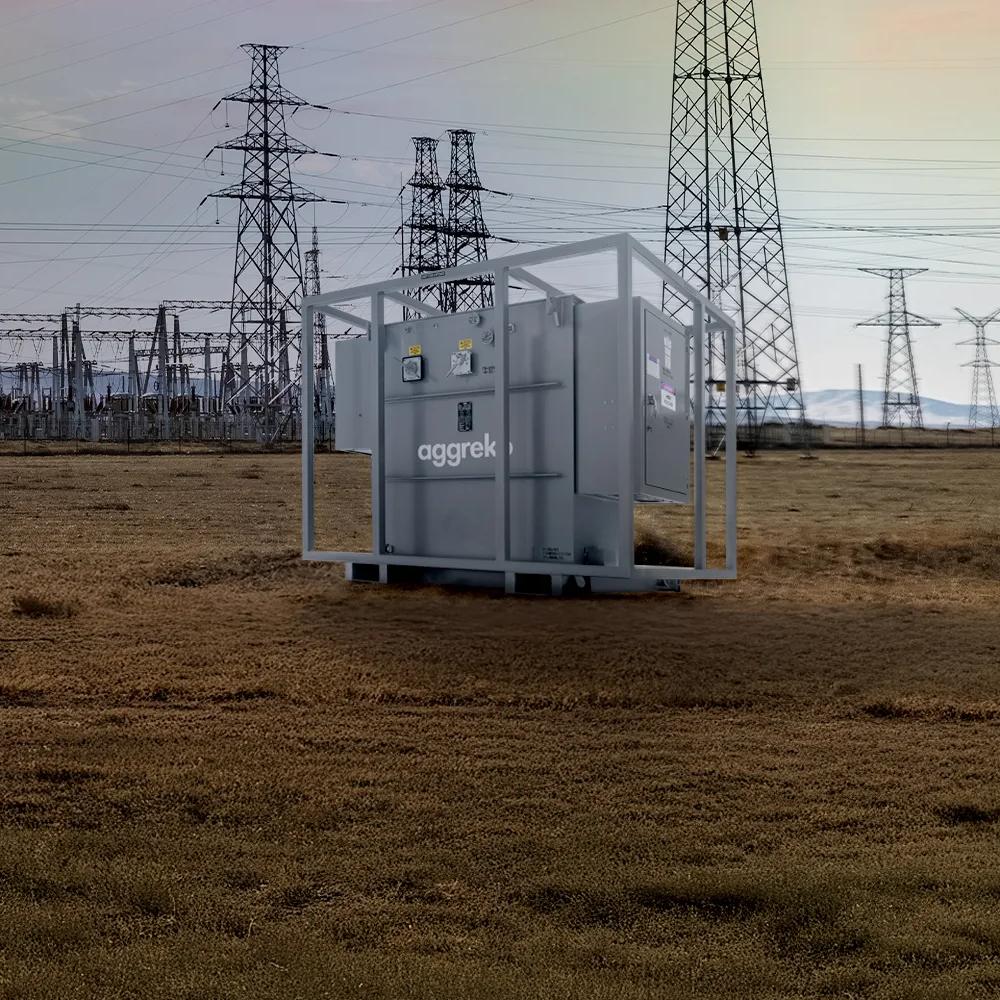 Transformer in a field with a power plant in the background