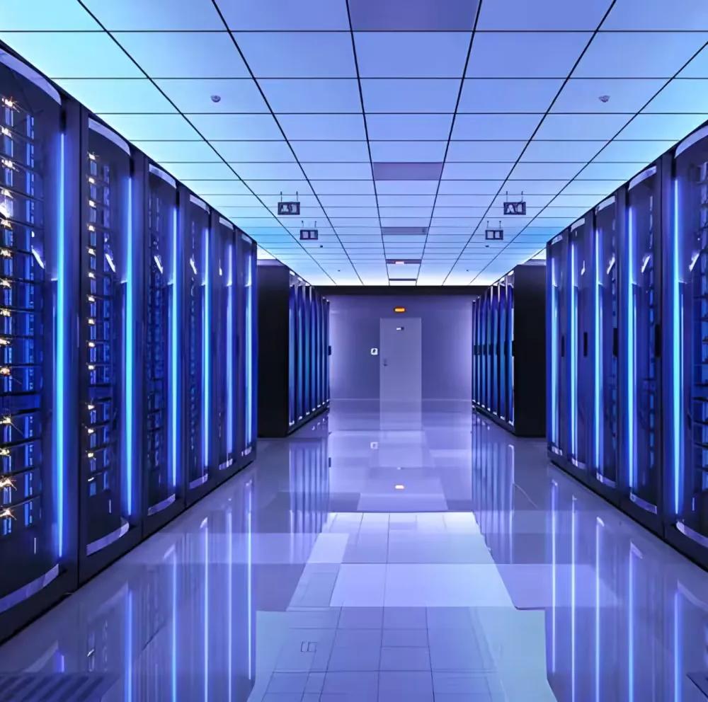 A long, symmetrical perspective view down an aisle in a massive server room, with towering rows of racks illuminated by a cool blue light from vertical LED strips, and the floor reflecting the light.