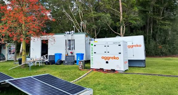 Two power and energy units at a residential property, beside a solar panel.