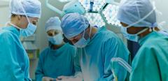 Group of surgeons performing surgery on patient in operating room