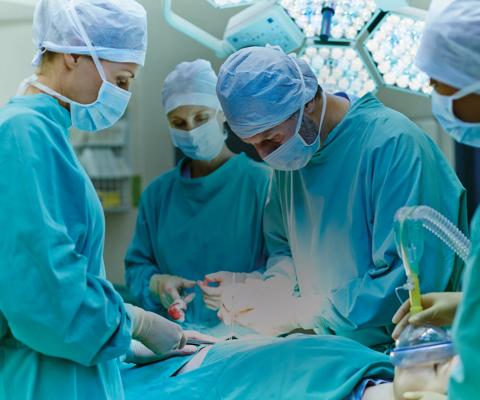 Group of surgeons performing surgery on patient in operating room