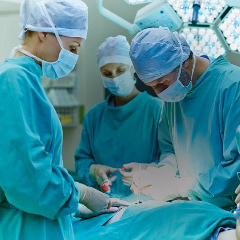 Group of surgeons performing surgery on patient in operating room