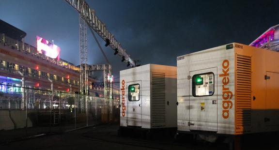 Two White Aggreko units sitting backstage of a concert. 