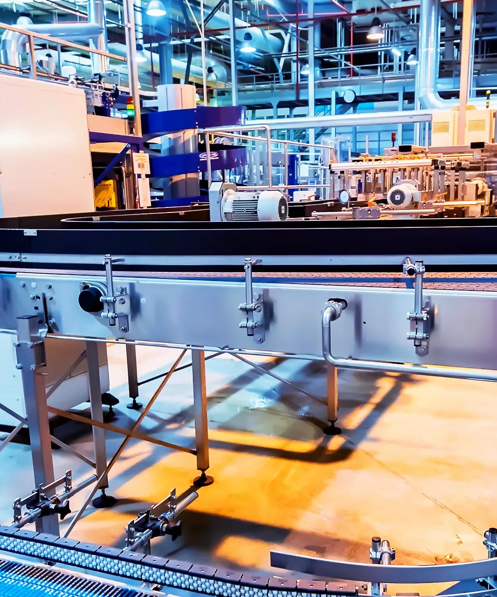 Un large système de convoyeur automatisé tourne dans un coin d’une usine bien éclairée.