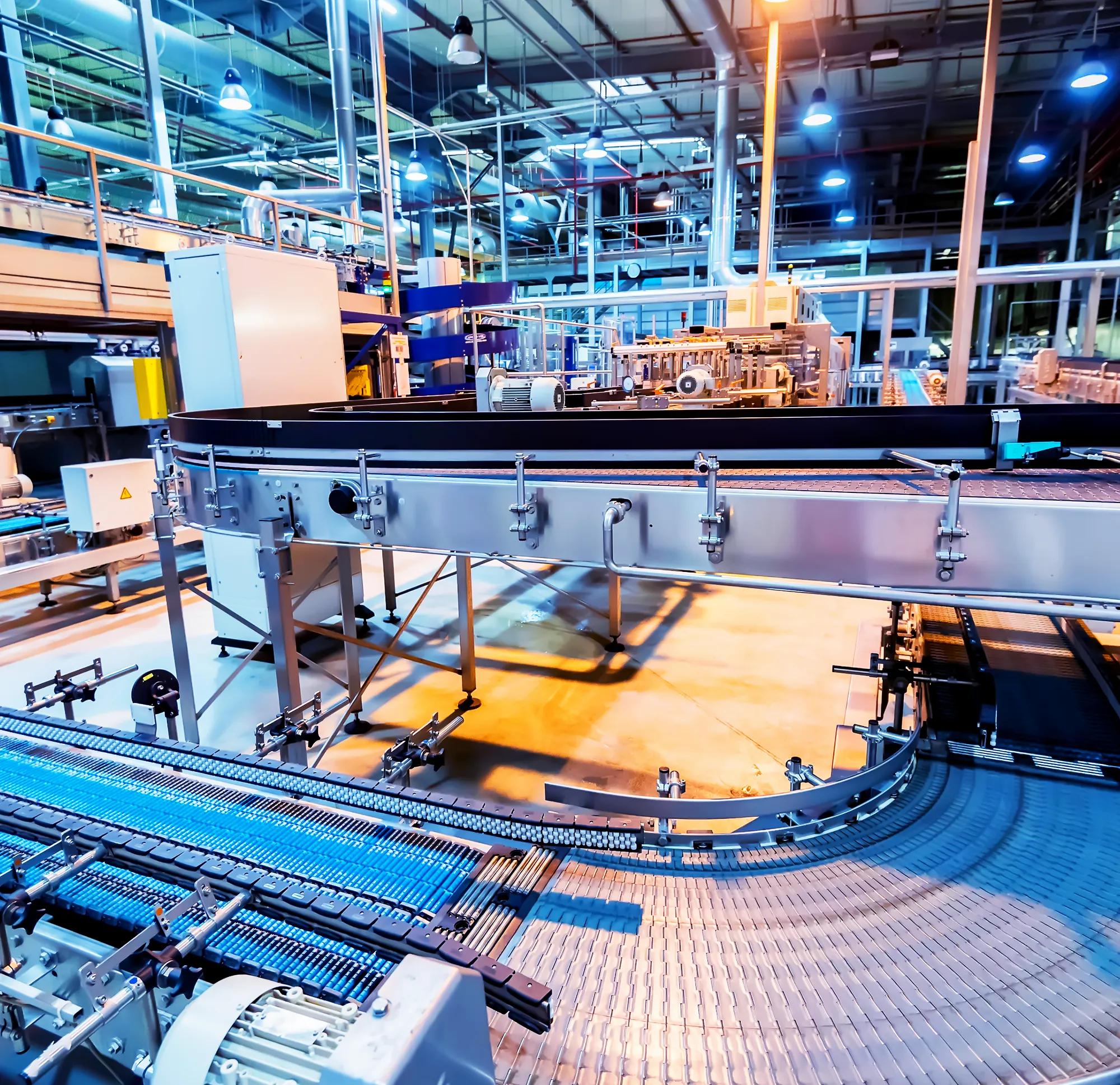 A wide, automated conveyor belt system turning a corner in a brightly lit factory.