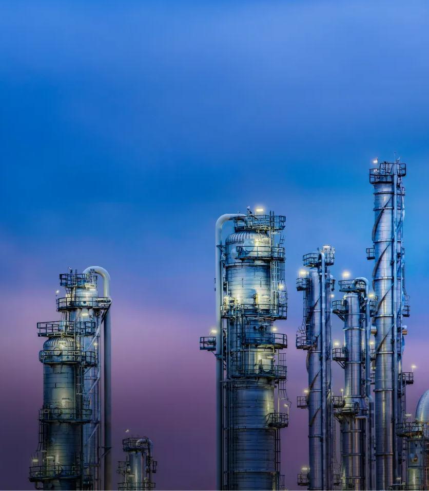 View of a refinery's towers under a blue, purplish sky