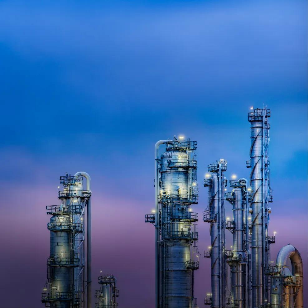 View of a refinery's towers under a blue, purplish sky