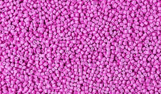 Background of plastic granules. Polymeric pellets. Colorant for plastics. Pink color.