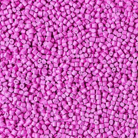 Background of plastic granules. Polymeric pellets. Colorant for plastics. Pink color.