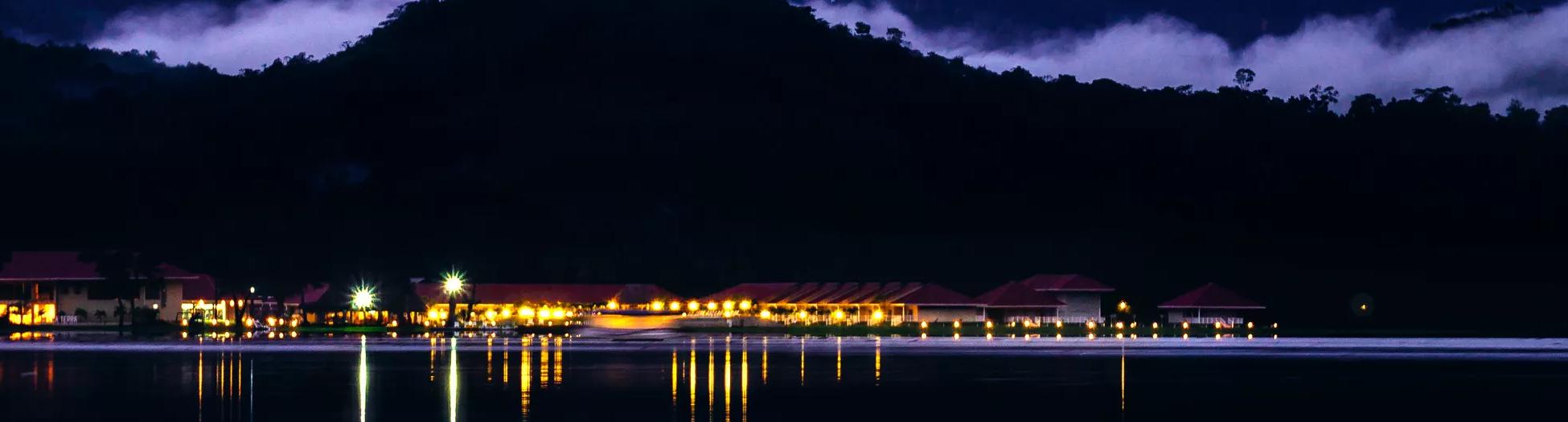 A hotel at night with their lights reflecting off the calm lake. Shot at blue hour in the Amazon rainforest