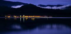 A hotel at night with their lights reflecting off the calm lake. Shot at blue hour in the Amazon rainforest