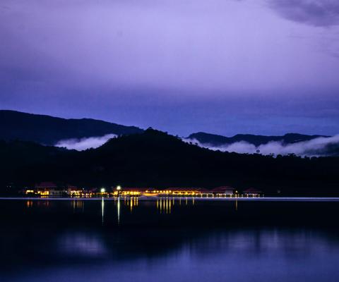 A hotel at night with their lights reflecting off the calm lake. Shot at blue hour in the Amazon rainforest