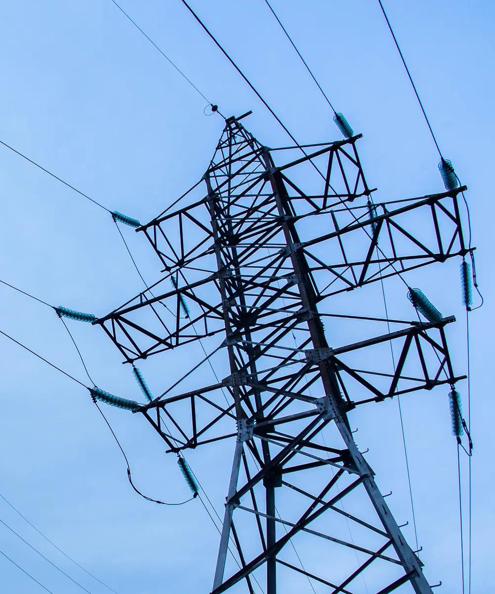 Three transmission towers against a blue sky, and rows of more towers in the background 