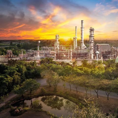 Oil refiner industry in rural scene on sunset background