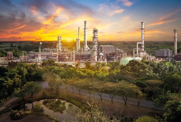 Oil refiner industry in rural scene on sunset background