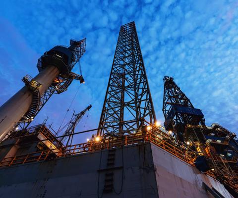 A jackup offshore oil drilling rig is docked at port for maintenance & repairs prior to reassignment.