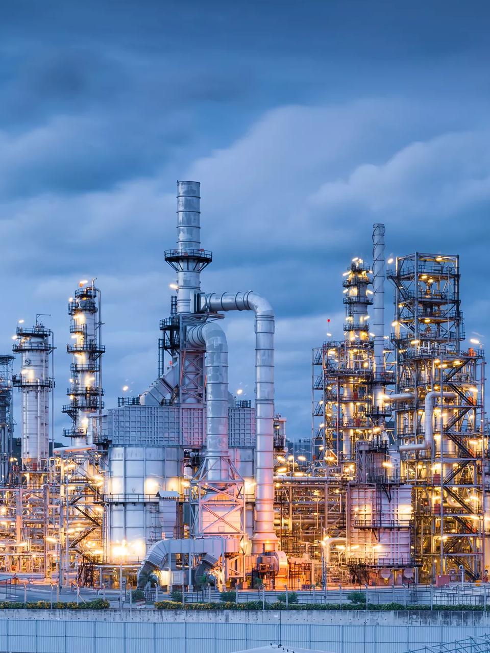 A wide view of an intricate petrochemical refinery at twilight.