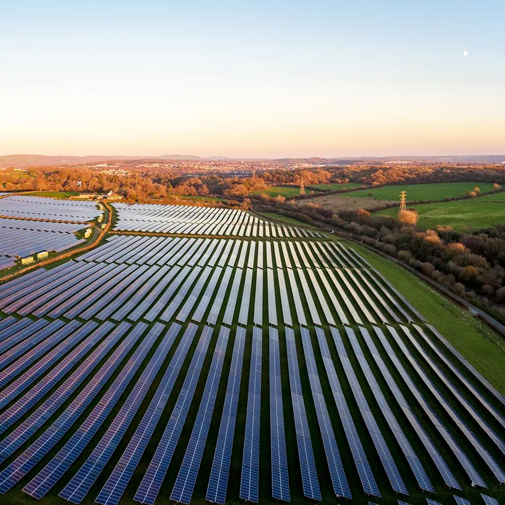 Aerial view of multiple rows of solar panels across a grass field.