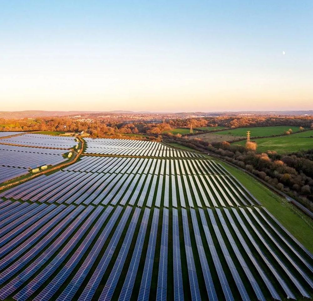 Aerial view of multiple rows of solar panels across a grass field.