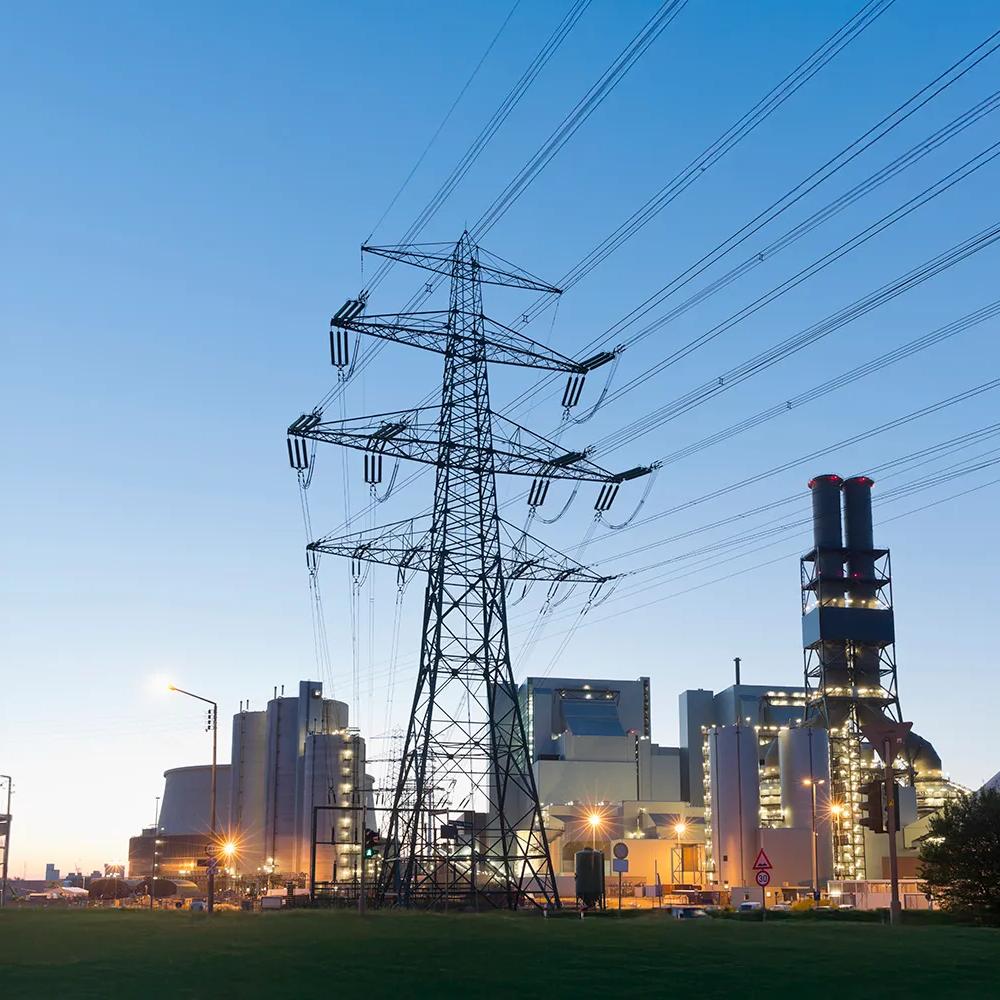 View at sunrise of a transmission power in front of a facility.
