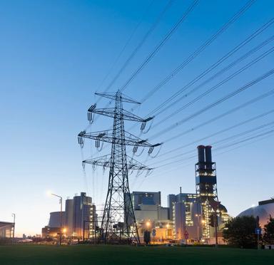 View at sunrise of a transmission power in front of a facility.