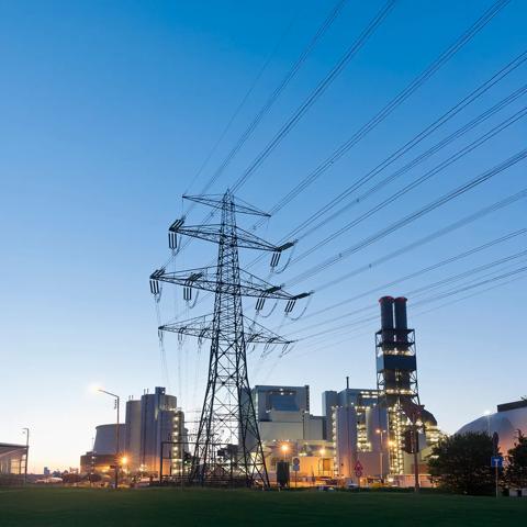 View at sunrise of a transmission power in front of a facility.