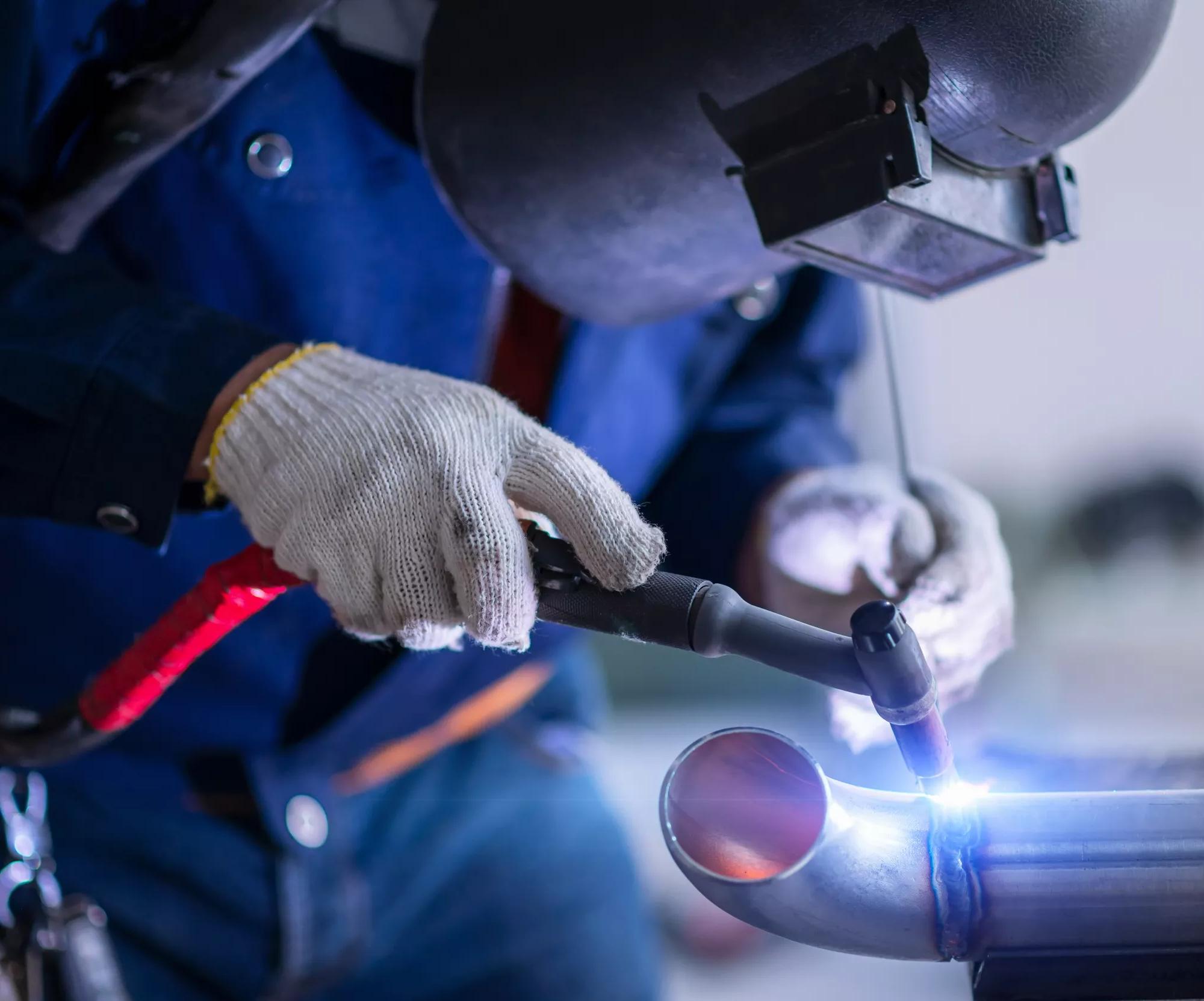 A worker with a safety mask on welding a piece of metal.