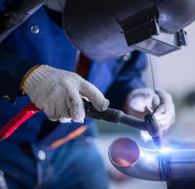 A worker with a safety mask on welding a piece of metal.
