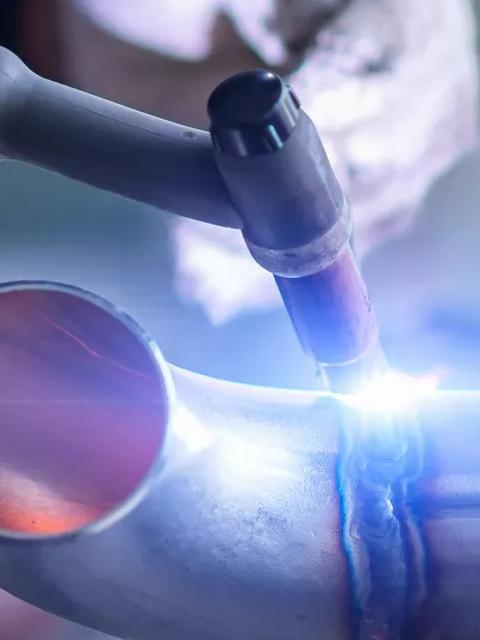 Close-up of a worker welding metal with protective gloves.