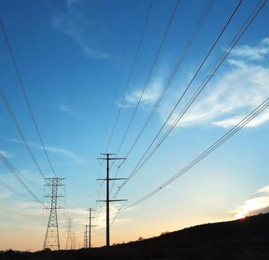 Silhouette of power lines against a vibrant sunset sky with wispy clouds.