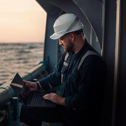 Marine chief officer or captain on deck of vessel or ship watching laptop. Internet and home connection at sea.