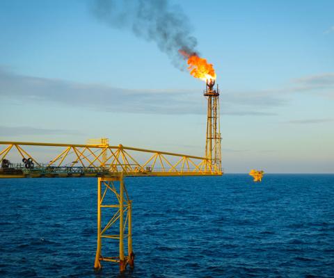 Gas is releasing and burning to the atmosphere from flare bridge of offshore gas platform.