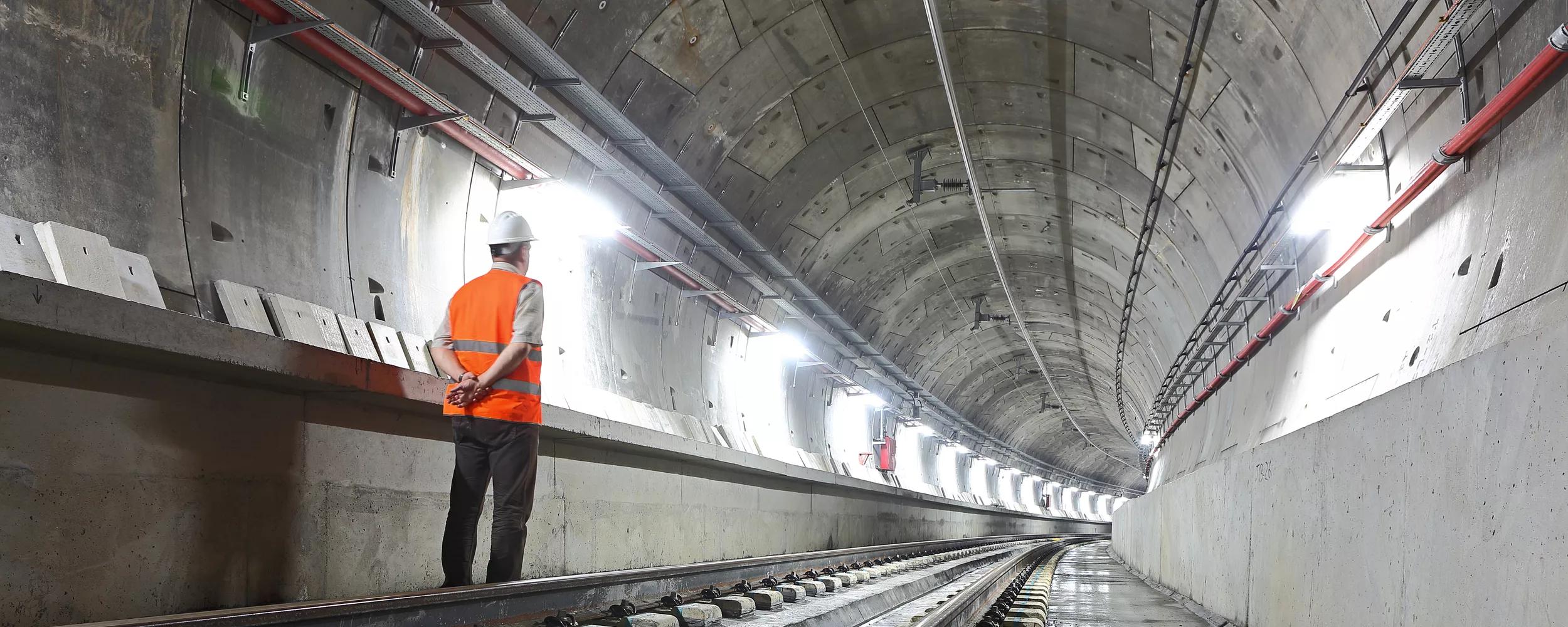 Underground metro tunnel. An engineer is staring at the level of rails looking towards the end of line.