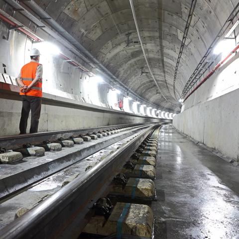 Underground metro tunnel. An engineer is staring at the level of rails looking towards the end of line.