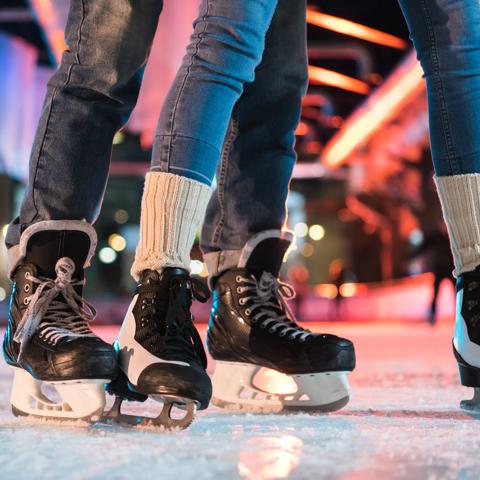 close-up partial view of young couple in skates ice skating on rink
