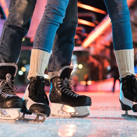 close-up partial view of young couple in skates ice skating on rink