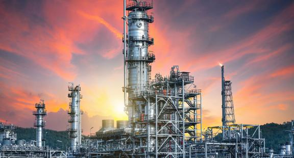 View of a refinery at a distance, with an orange sky in the background.