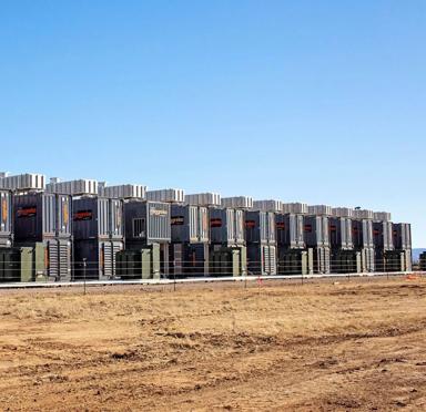 A row of black Aggreko gas generators on a dirt road against a blue sky
