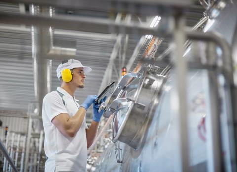 View of a worker in uniform checking the factory’s machinery.