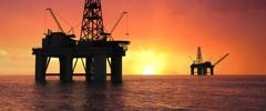 Oil rig silhouette over orange sky